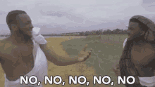 two shirtless men are standing next to each other in a field and one of them is saying no .