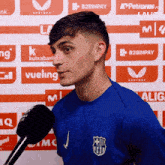 a man in a blue shirt is talking into a microphone in front of a wall that says b2binpay