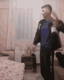 a man in a blue shirt and black pants is dancing in a bedroom