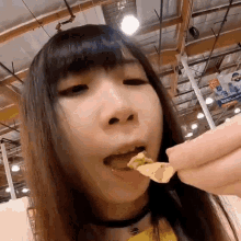 a close up of a woman eating chips with a sign in the background that says coca cola