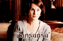a woman is sitting on a bed with a foreign language written on the bottom of her face .