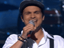 a man singing into a microphone while wearing a hat