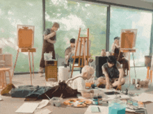 a group of people are painting in a room with a large window