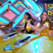 two women are dancing in front of a sign that says " po ingo legal "
