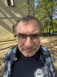 a man wearing glasses and a plaid shirt that says gdynia on it