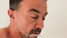 a man with a beard says i 'm speechless in front of a white wall