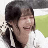 a young woman is laughing with her eyes closed and her mouth open .