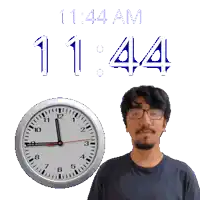 a man wearing glasses stands in front of a wall clock that reads 11:14 am