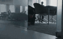 a man is sitting at a table in a conference room behind a glass wall .