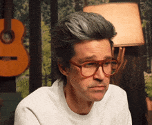 a man wearing glasses and a white shirt has a sad look on his face