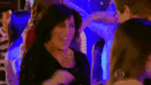 a woman in a black dress is dancing in a dark room with blue lights