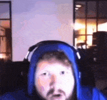 a man with a beard wearing headphones and a blue hoodie .