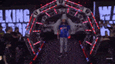 a man in a blue shirt is walking through an archway with the word king on the screen behind him