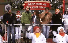 a group of people are standing in front of a banner that says macy 's celebrates the holiday season