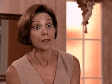 a woman making a surprised face in front of a window