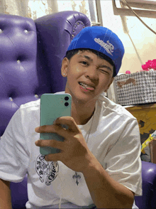 a boy wearing a blue hat and a white shirt is taking a selfie