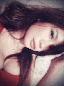 a woman in a red top is laying on a pillow