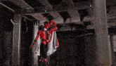 a person in a red and black superhero costume is standing in a dark room