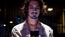 a man with a beard is looking at a cell phone