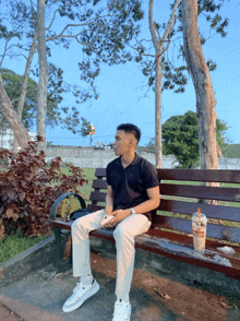 a man sits on a park bench with a cup of coffee on the ground