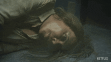 a woman laying on the floor with her mouth open and a netflix logo in the background