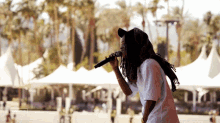 a man with dreadlocks singing into a microphone in front of a crowd