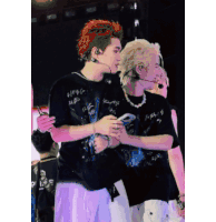 a man with red hair is hugging another man on stage