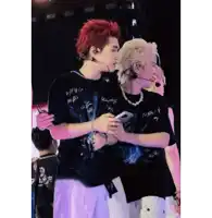 a man with red hair is hugging another man on stage