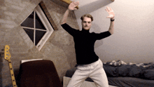 a man in a black shirt and white pants is dancing in front of a window