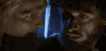two men are looking at each other in a dark room with a blue light behind them .