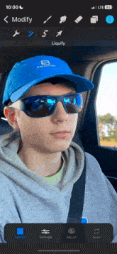 a man wearing sunglasses and a blue salomon hat is in a car