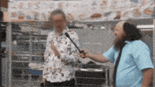 a man in a blue shirt is talking to another man in front of a sign that says abc
