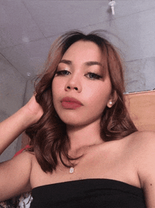 a woman wearing a black off the shoulder top and a necklace with a diamond pendant