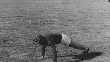 a man is doing push ups on the grass in a field .