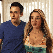 a man in a blue shirt stands next to a woman in a colorful top