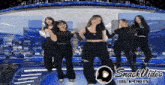 a group of women are dancing on a stage with snack video logo in the corner
