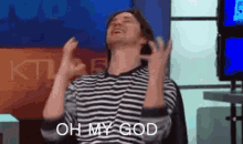 a man in a striped shirt is sitting in a chair with his hands in the air .