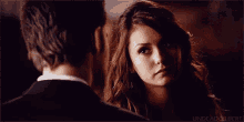 a man and a woman are looking at each other and the woman is looking at the man 's face .