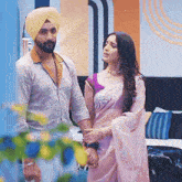 a man in a turban is standing next to a woman in a pink saree