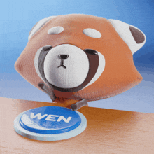a stuffed animal is pressing a blue button that says wen