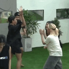 a group of people are dancing in front of a potted plant