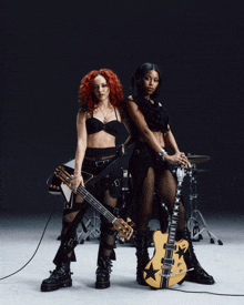 a woman is playing a bass guitar in front of a drum set