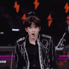 a young man in a black and silver jacket is making a funny face