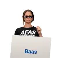 a woman wearing a afas software shirt holds a sign