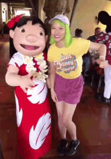a woman in a yellow shirt that says walt disney world poses with a lilo mascot