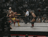 two men are wrestling in a ring with a referee in front of a crowd