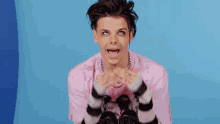 a young man in a pink and black striped shirt is making a funny face with his mouth open