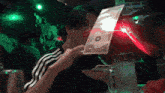 a man is holding a piece of paper with a dollar sign on it in front of his face