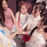 a group of young girls are holding hands in a circle