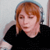 a woman wearing headphones and a black shirt is looking at something .